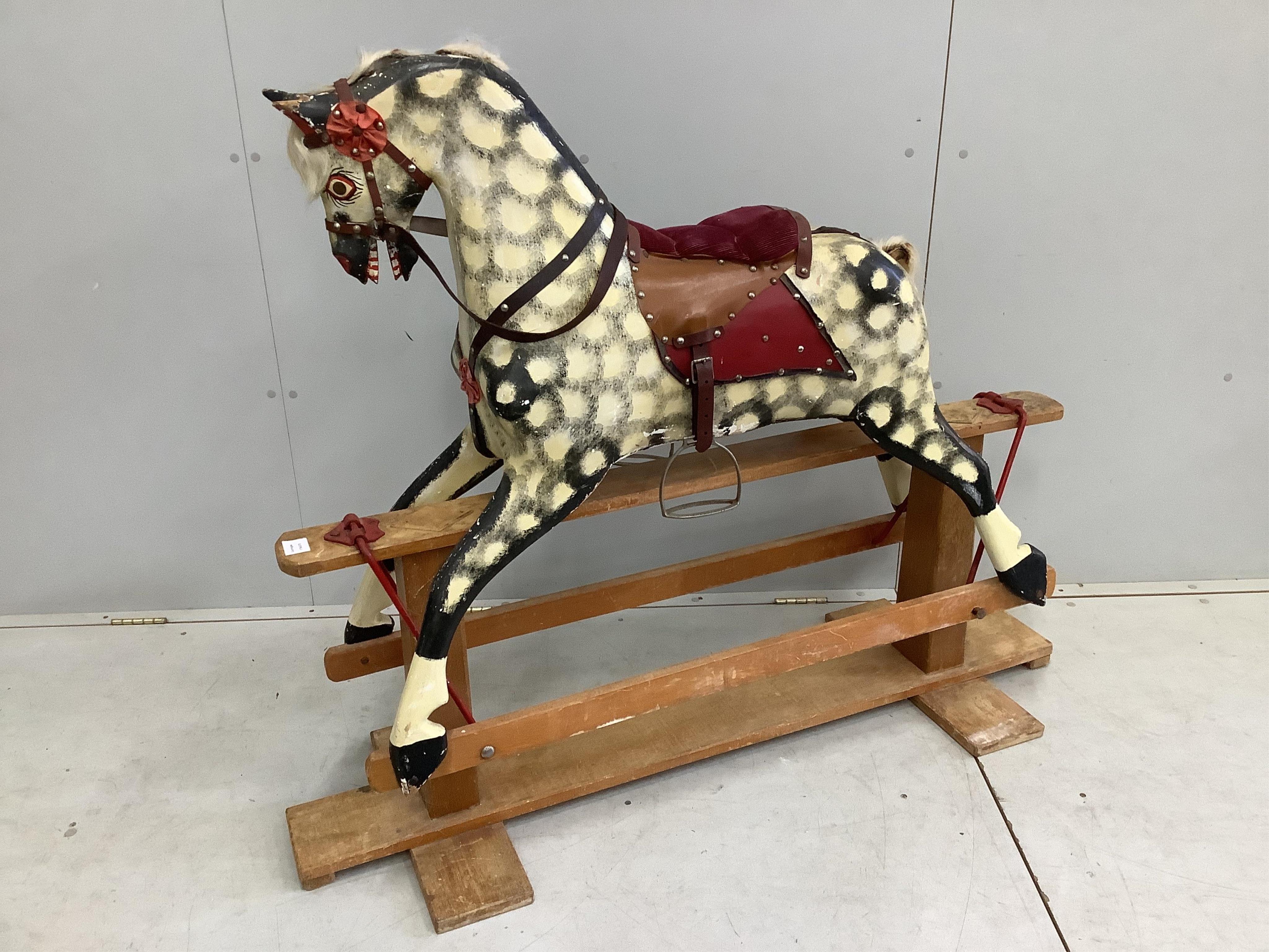 A mid-20th century dapple grey rocking horse, probably by Collinson, with corduroy and leather saddle and painted wooden body, 112cm high, the stand 137cm long. Condition fair, losses to the paint work and notable damage
